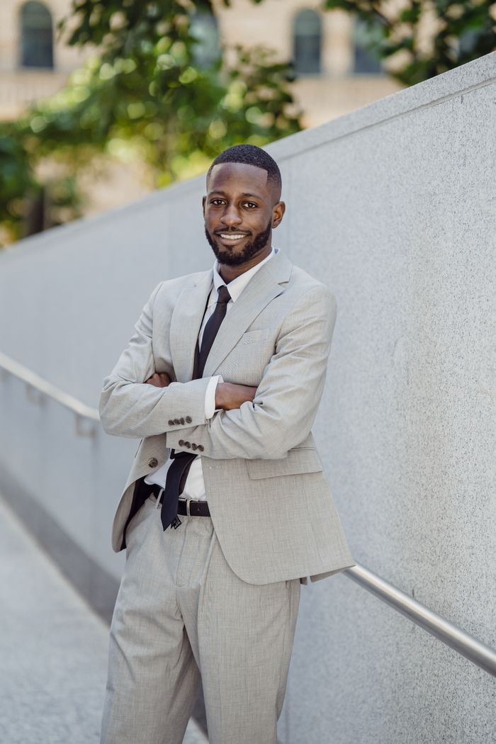 Smiling businessman in gray suit poses confidently outdoors, conveying success and professionalism.